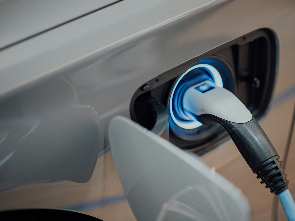 Ein weißes Elektro-Auto wird aufgeladen, dabei leuchtet der Ring um den Stecker blau-weiß.